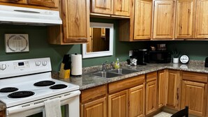 A kitchen with wooden cabinets, a white stove, a microwave, and a sink. - Cozy 2-bedroom with WiFi, Aurora viewing, central location in Fairbanks (Fairbanks)