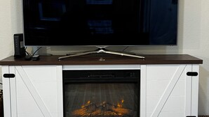 A flat-screen TV on a wooden entertainment center with a fireplace below. - Cozy 2-bedroom with WiFi, Aurora viewing, central location in Fairbanks (Fairbanks)