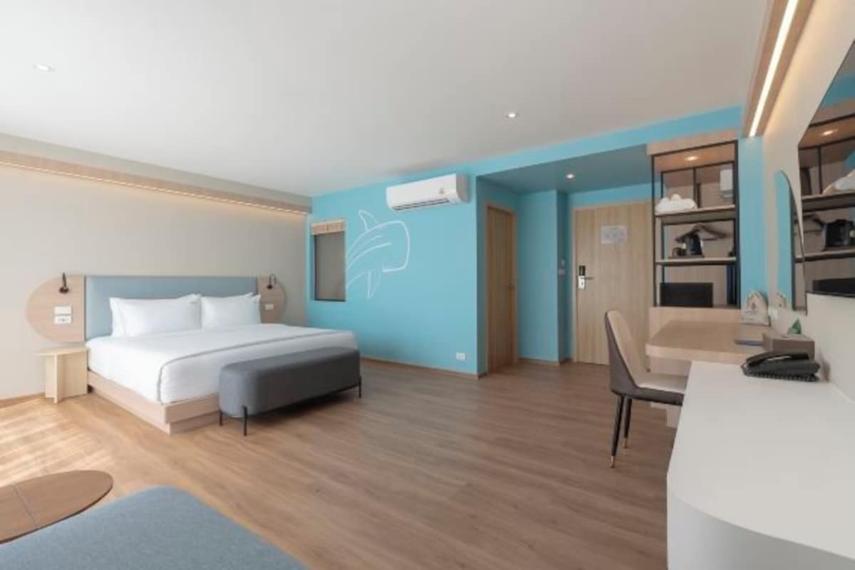 Una habitación de hotel moderna con una cama grande, un escritorio y un armario.
