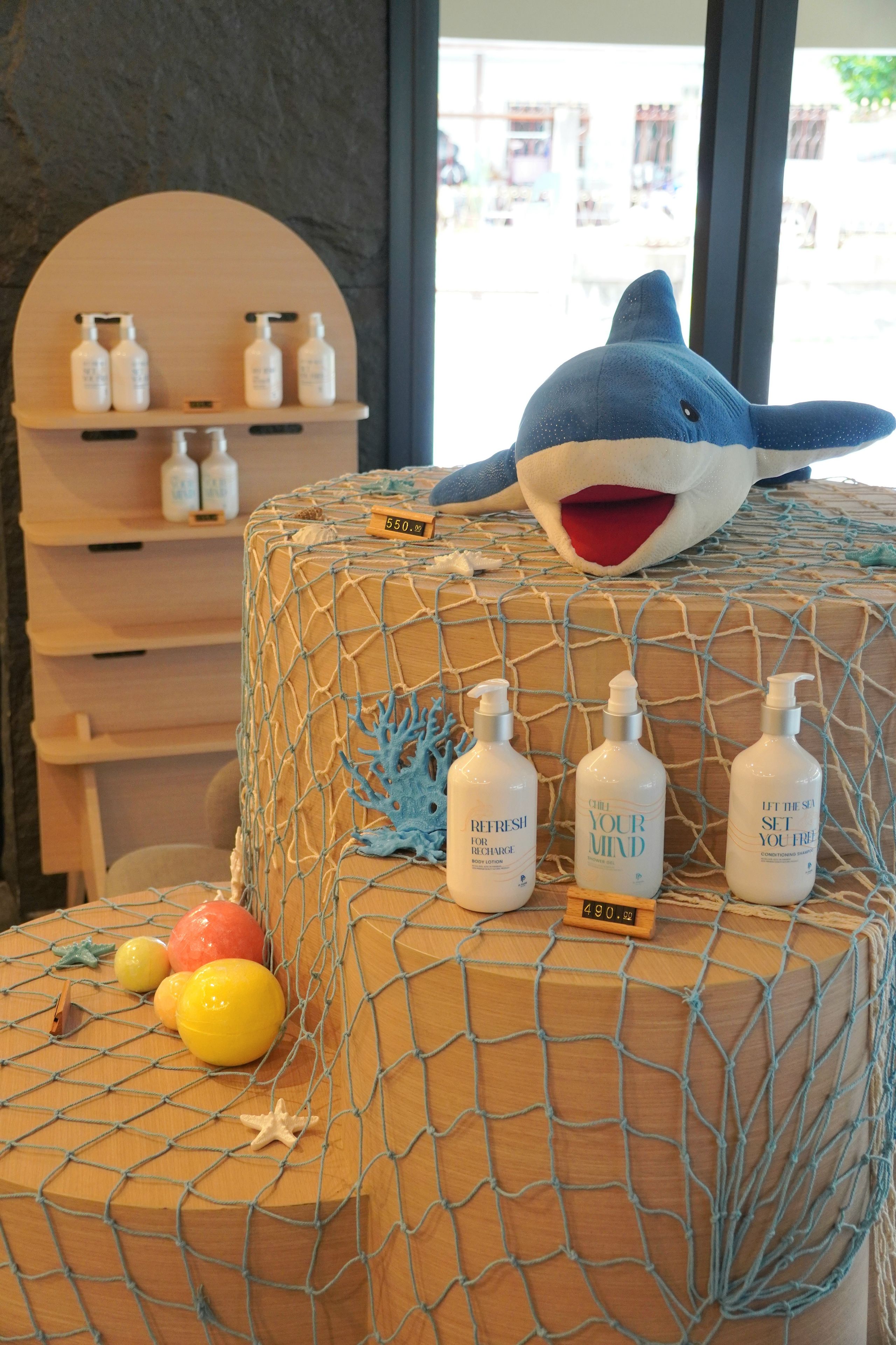 A beach-themed cake with a shark decoration, surrounded by bottles of body lotion and a price tag.