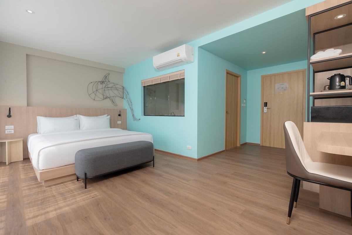 Une chambre d’hôtel moderne équipée d’un lit, d’un bureau, d’une chaise, d’un climatiseur et d’une fenêtre avec des stores.