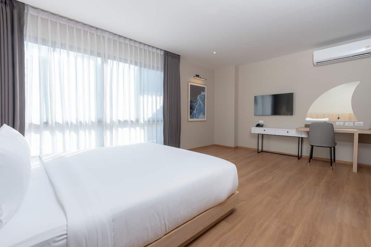 Une chambre d’hôtel moderne, dotée d’un grand lit, d’un bureau, d’une chaise, d’une télévision et d’un tableau au mur.