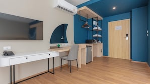 Une chambre moderne avec un bureau blanc, une chaise grise, une armoire intégrée et un mur d’accent bleu.