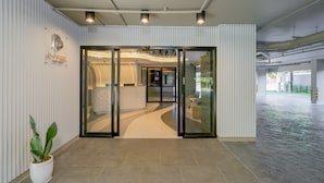 Un hall d’hôtel moderne avec un comptoir d’accueil, une plante en pot et un espace spacieux doté d’un sol à motifs.