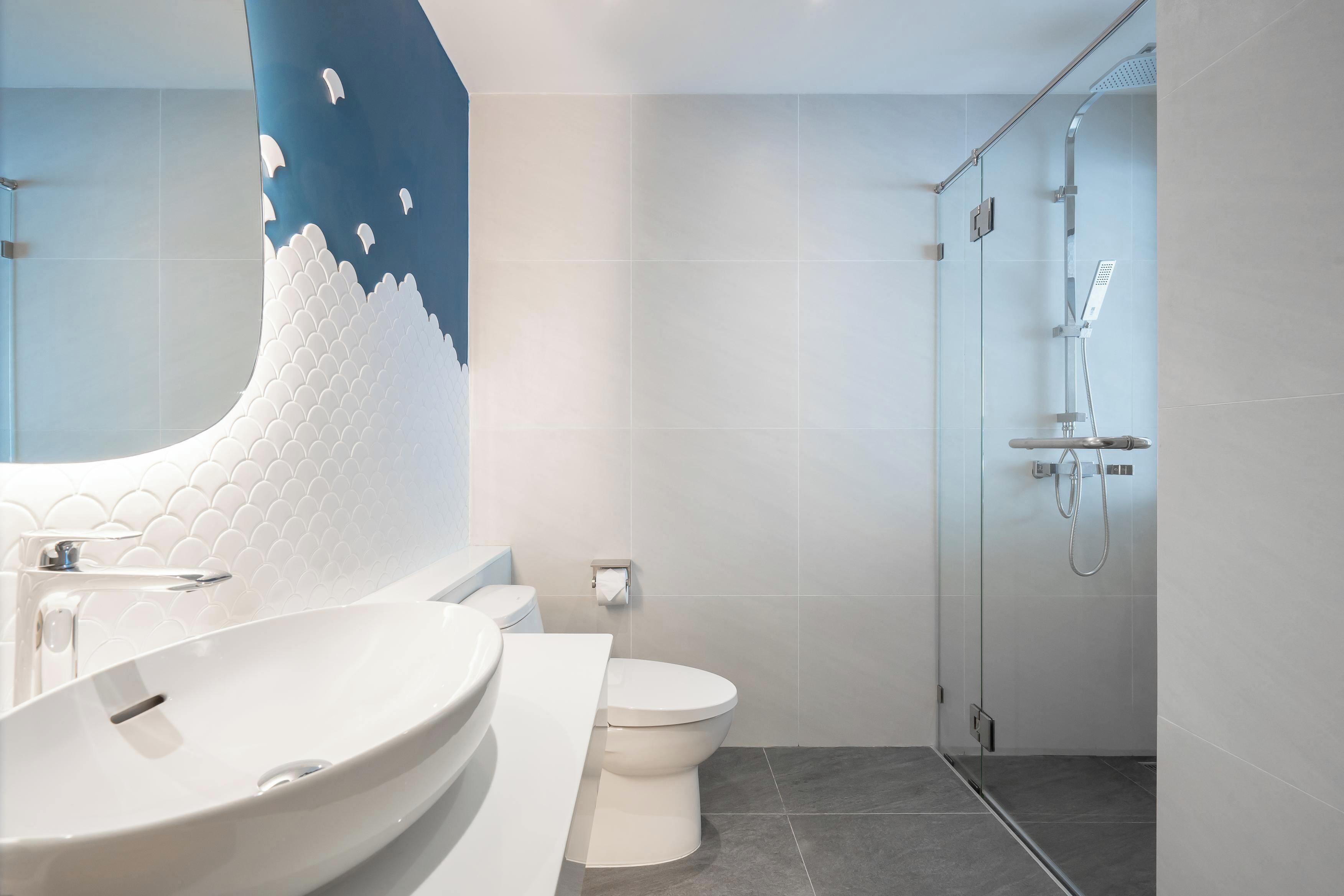 Un baño moderno con un lavamanos grande, inodoro y ducha con cerramiento de vidrio.