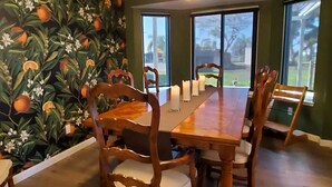 A dining room with a long wooden table, six chairs, and a mural of oranges and flowers on the wall. - Home Among the Orchards, Pool, National Parks, Friendliest of Towns (Exeter)