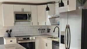 Eine moderne Küche mit weißen Schränken, Edelstahlgeräten, einer Marmorarbeitsplatte und Holzdielen.