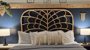 Ein Schlafzimmer mit dunkelblauer Kopfteil, weißer Bettwäsche und zwei Nachttischlampen.