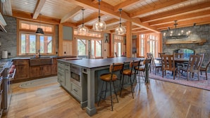Une cuisine spacieuse dotée d’un grand îlot central, de poutres en bois au plafond et d’éléments décoratifs en pierre.