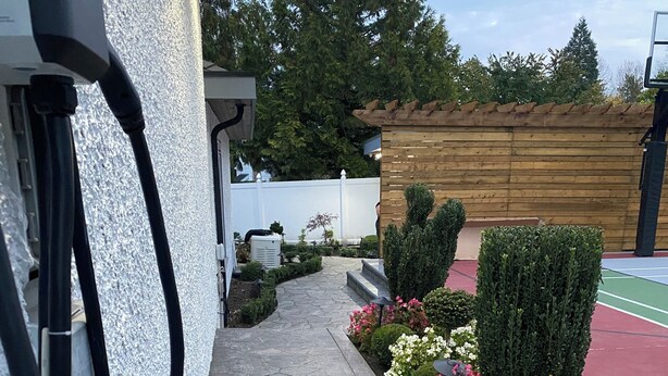Een geplaveid pad dat leidt naar een gebouw met een witte gevel en een houten terras.