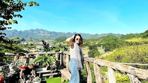 A person standing on a wooden deck with a view of a mountainous landscape. - Doi Thong Moc Chau - by BAY LUXURY (Moc Son)
