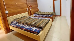 A bedroom with two wooden beds, a wooden headboard, a small shelf, and a door. - Doi Thong Moc Chau - by BAY LUXURY (Moc Son)