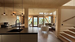 Een moderne keuken met een centraal eiland, een eetgedeelte met stoelen, een bank en een trap.