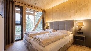 Een slaapkamer met een groot bed, houten wanden en een raam met gordijnen.