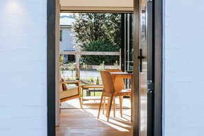 An interior space with a wooden table and chairs, a sofa, and a view of the outdoors through a glass door. - Comfort on Rowley (Wānaka)