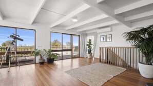 Una habitación amplia con ventanas grandes, suelo de madera, un telescopio y varias plantas en macetas.