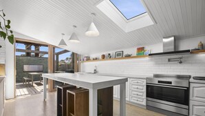 Una cocina moderna con una isla central, electrodomésticos de acero inoxidable y un tragaluz.