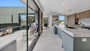 A modern kitchen with a large island, wooden cabinets, and a view of the outdoors.