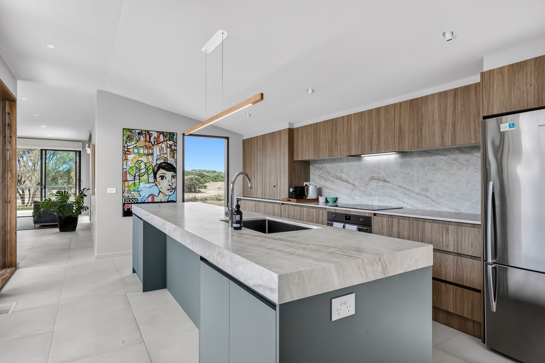 A modern kitchen with a marble countertop, stainless steel appliances, and a large island.
