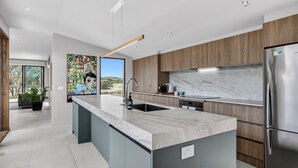 A modern kitchen with a marble countertop, stainless steel appliances, and a large island.