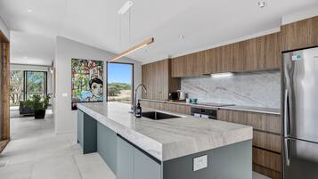 A modern kitchen with a marble countertop, stainless steel appliances, and a large island.