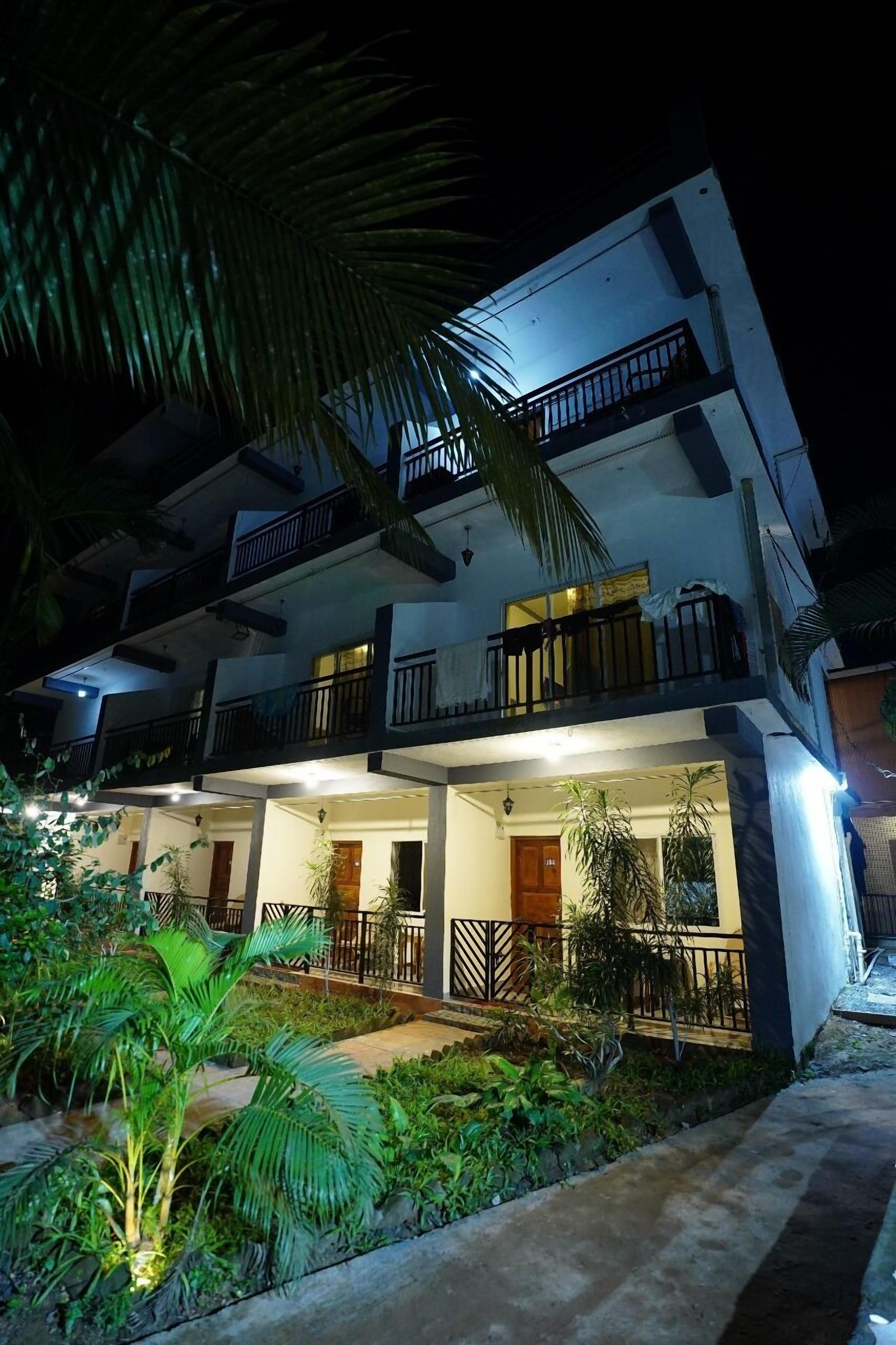 A multi-story building with balconies and a well-lit entrance.