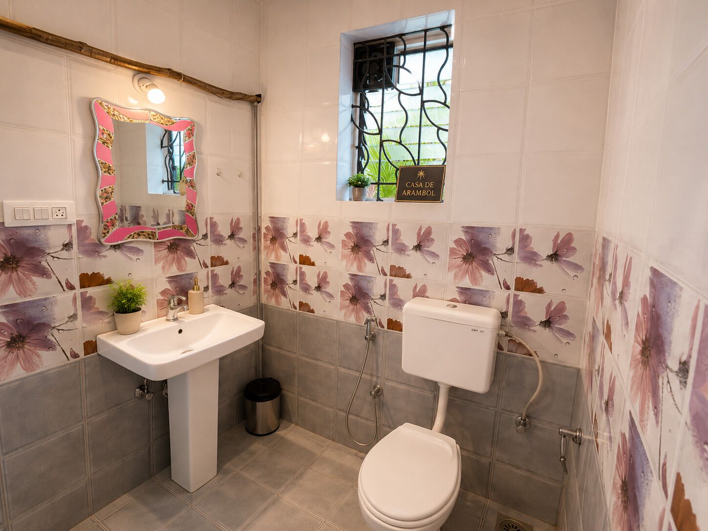 Um banheiro com pia branca, vaso sanitário e espelho com moldura floral.