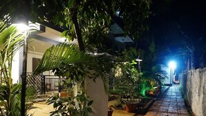 Un chemin illuminé la nuit qui mène à une maison sur laquelle on peut lire l’inscription « Casa de Arambó ».