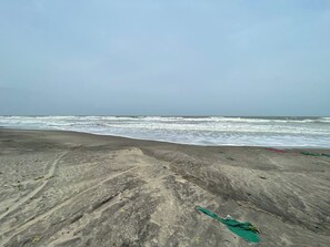 Una playa con arena al frente y olas del océano en el fondo.