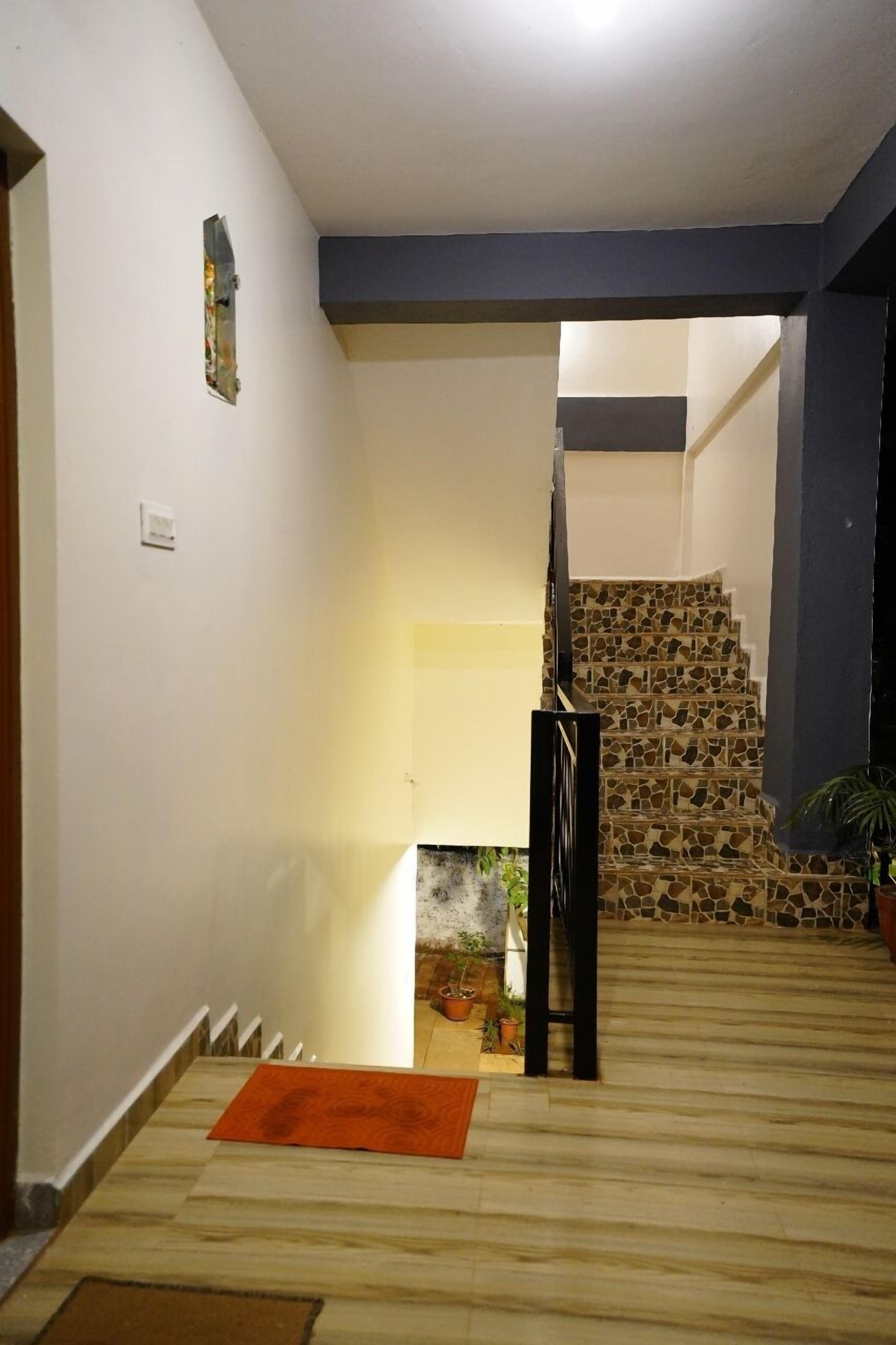 A staircase with a stone pattern, a wooden floor, and a small orange rug.