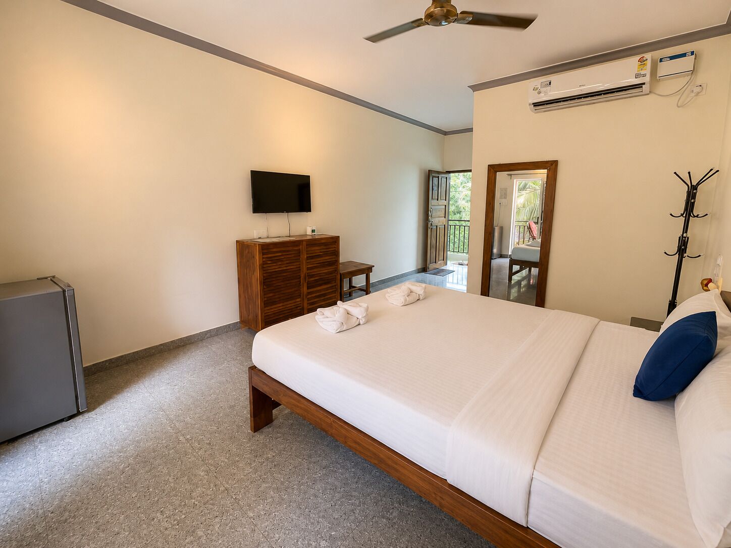 A hotel room with a bed, a television, a wardrobe, and an air conditioning unit.