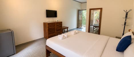 A hotel room with a bed, a television, a wardrobe, and an air conditioning unit.