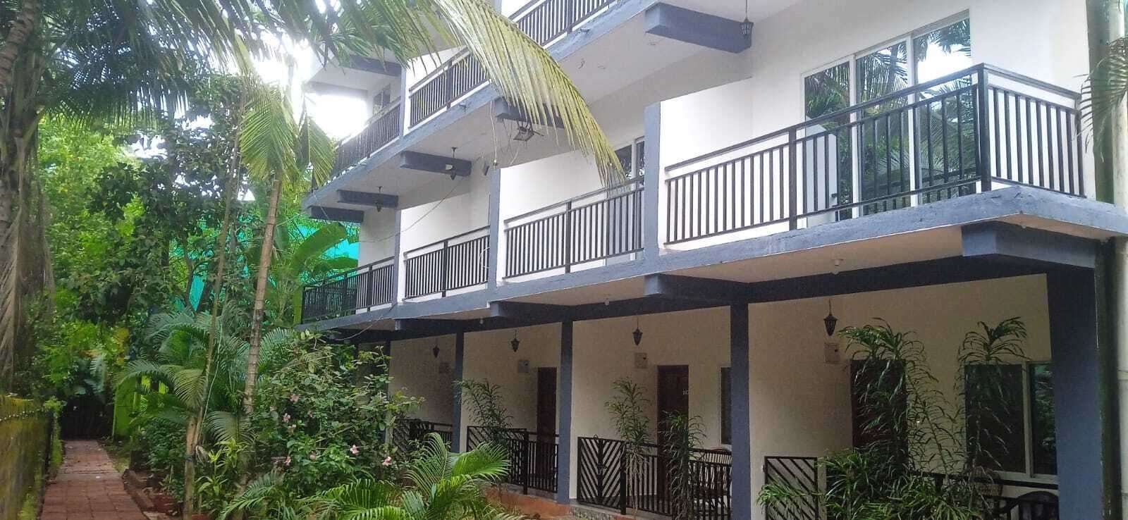 A multi-story building with balconies, surrounded by lush greenery.