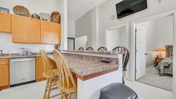 A kitchen with wooden cabinets, a granite countertop, and a dining area with chairs.