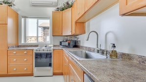 A kitchen with wooden cabinets, a stainless steel sink, a microwave, and a stove.