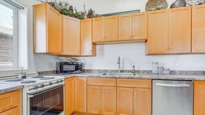 A kitchen with wooden cabinets, a stainless steel dishwasher, a built-in oven, and a microwave.