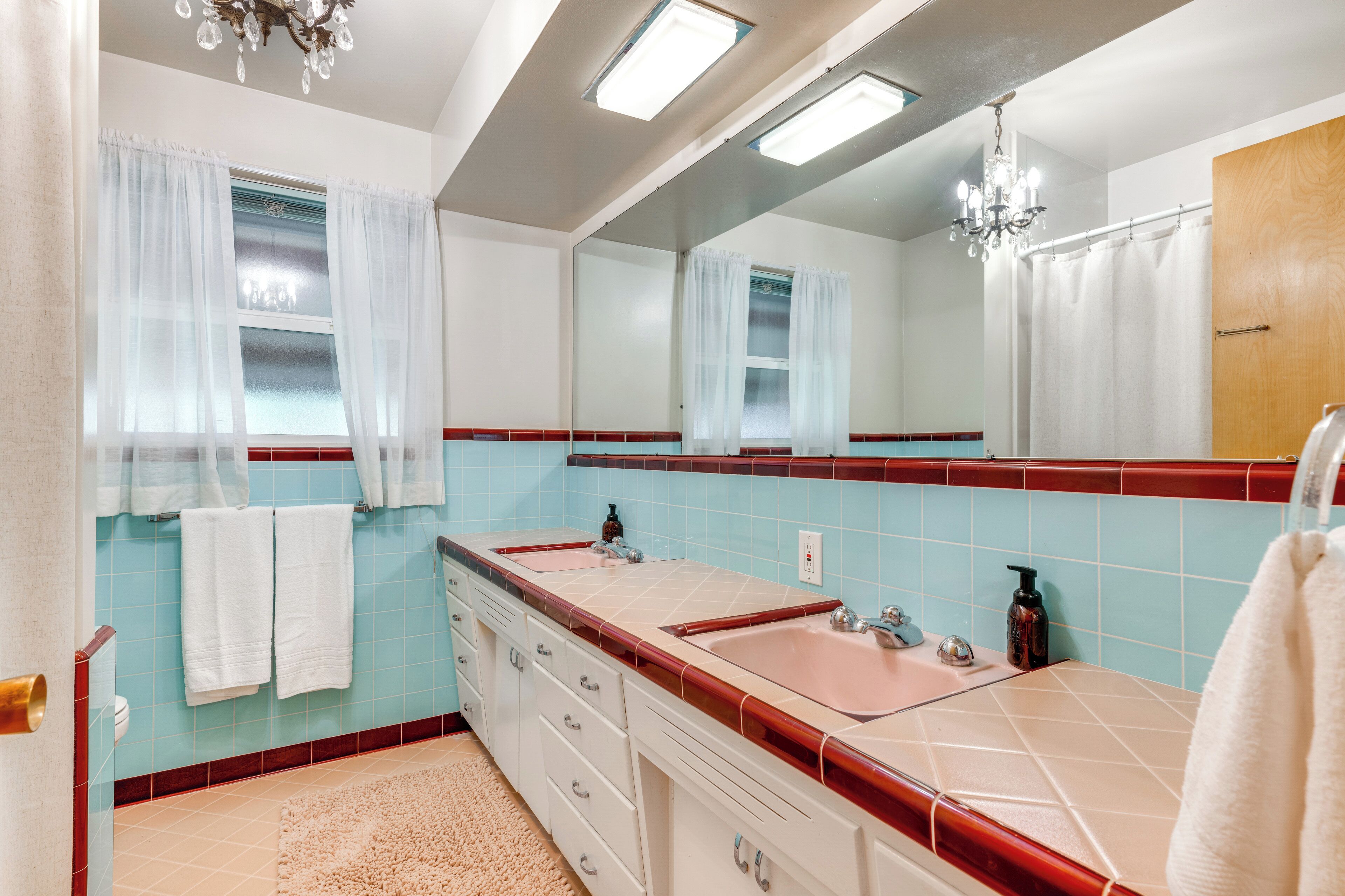 Ein Badezimmer mit zwei Waschbecken, einem großen Spiegel und einer Kristallleuchter.
