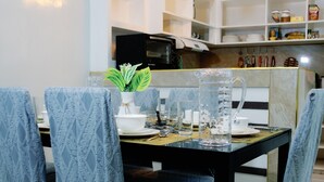 Een eetruimte met een tafel voor vier personen, met gestreepte stoelen en een heldere glazen kan.