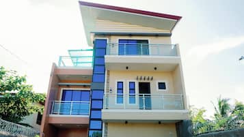 A multi-story residential building with balconies, large windows, and a flat roof.