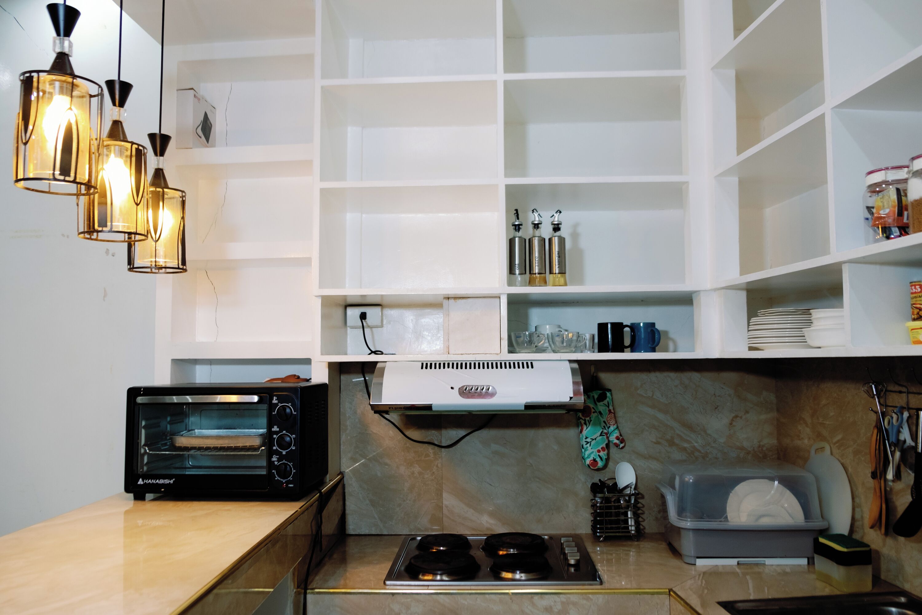 A kitchen with a built-in oven, a gas stove, and hanging utensils.