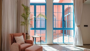 A room with a large window, a chair, a small table, and a potted plant. - Casa Amore Baia (Mandrem)