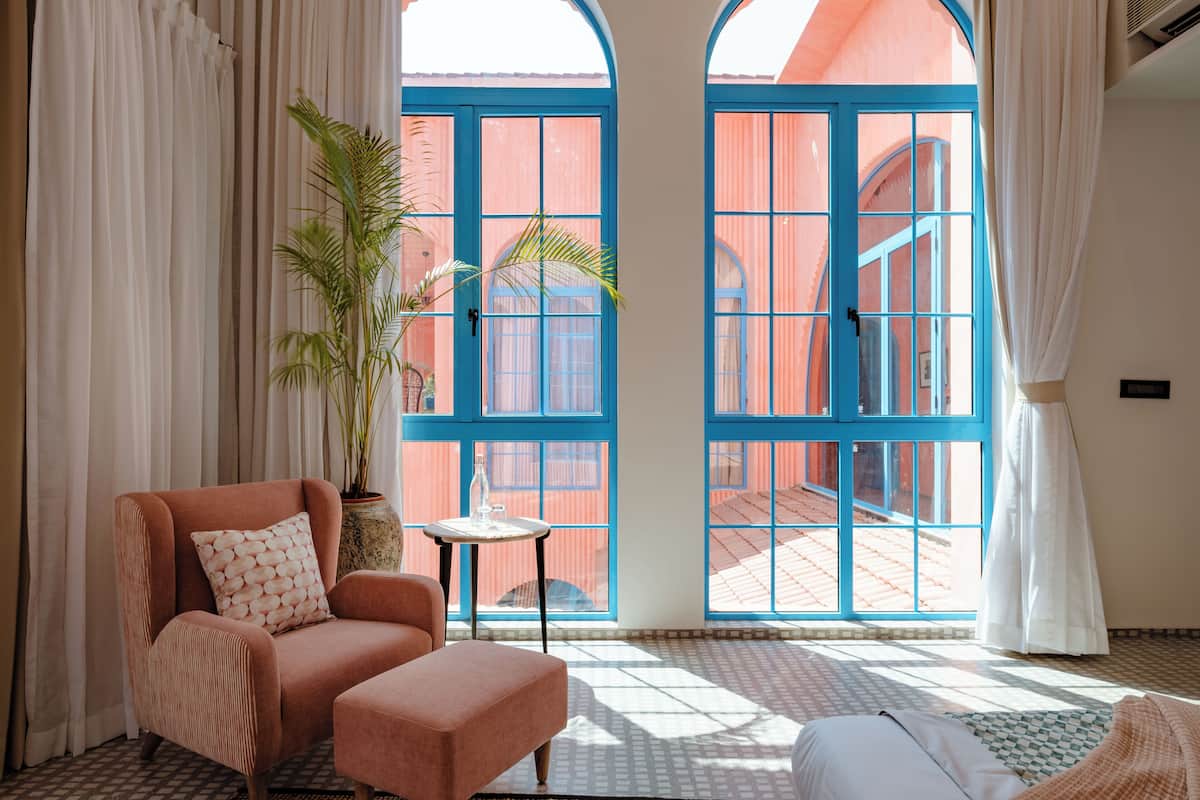 A room with a large window, a chair, a small table, and a potted plant.
