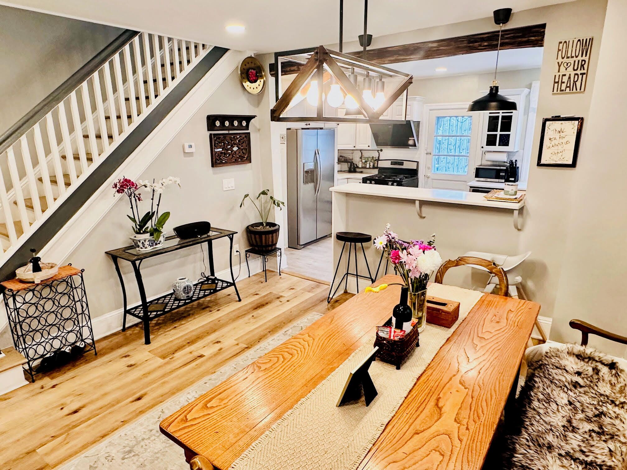 A modern kitchen with a built-in oven, a dining area with a wooden table and chairs, and a staircase leading to another level.