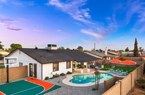 A residential backyard with a swimming pool, a basketball court, and outdoor seating. - Backyard Game Day HQ | Pool, Hoops & Putt Putt (Glendale)