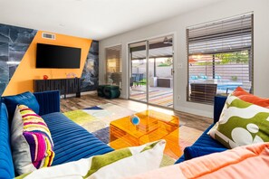 A modern living room with a sofa, coffee table, and a flat-screen TV mounted on a wall.