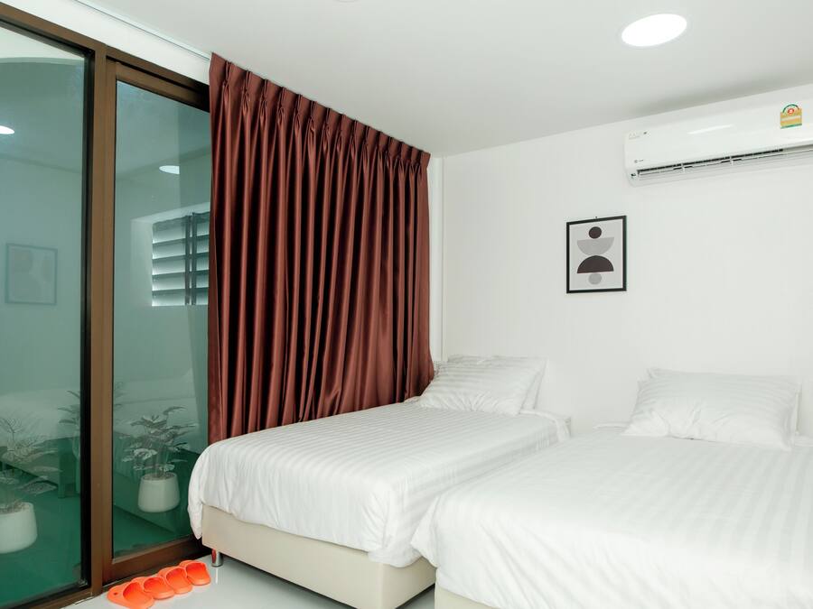 A bedroom with two beds, a sliding glass door, and an air conditioning unit on the wall.