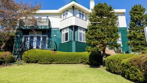 A two-story building with a green and white facade, a balcony, and a well-maintained lawn. - izukougen no chiisana o-beruju arusion (Ito)