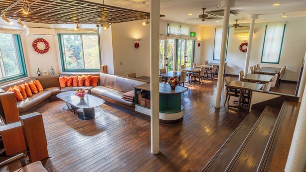 A spacious lobby with a large seating area, multiple tables, and a high ceiling with exposed beams. - izukougen no chiisana o-beruju arusion (Ito)
