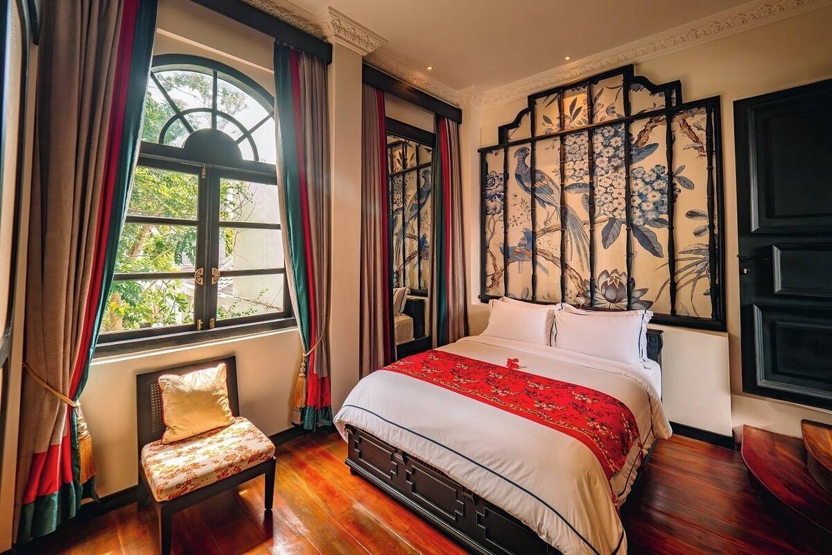 A traditional room with a bed, a chair, and a window with curtains.