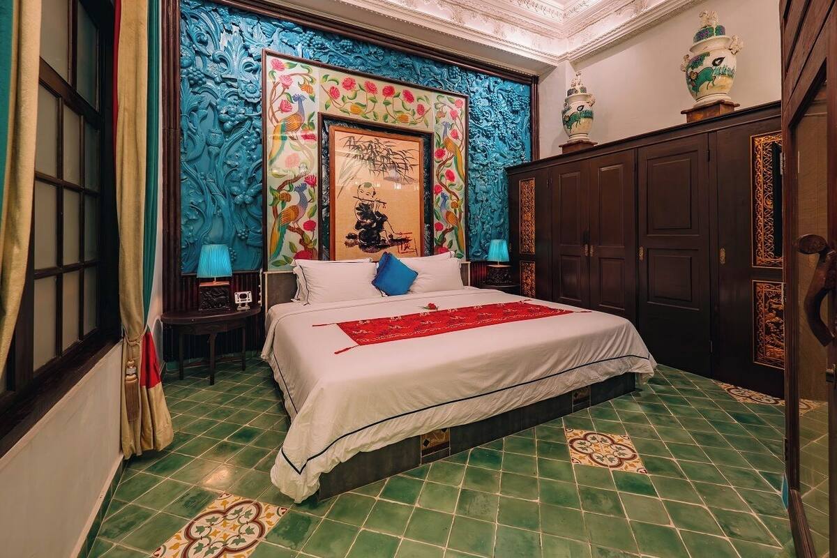 A bedroom with a large bed, a decorative wall, and a traditional vase on a cabinet.